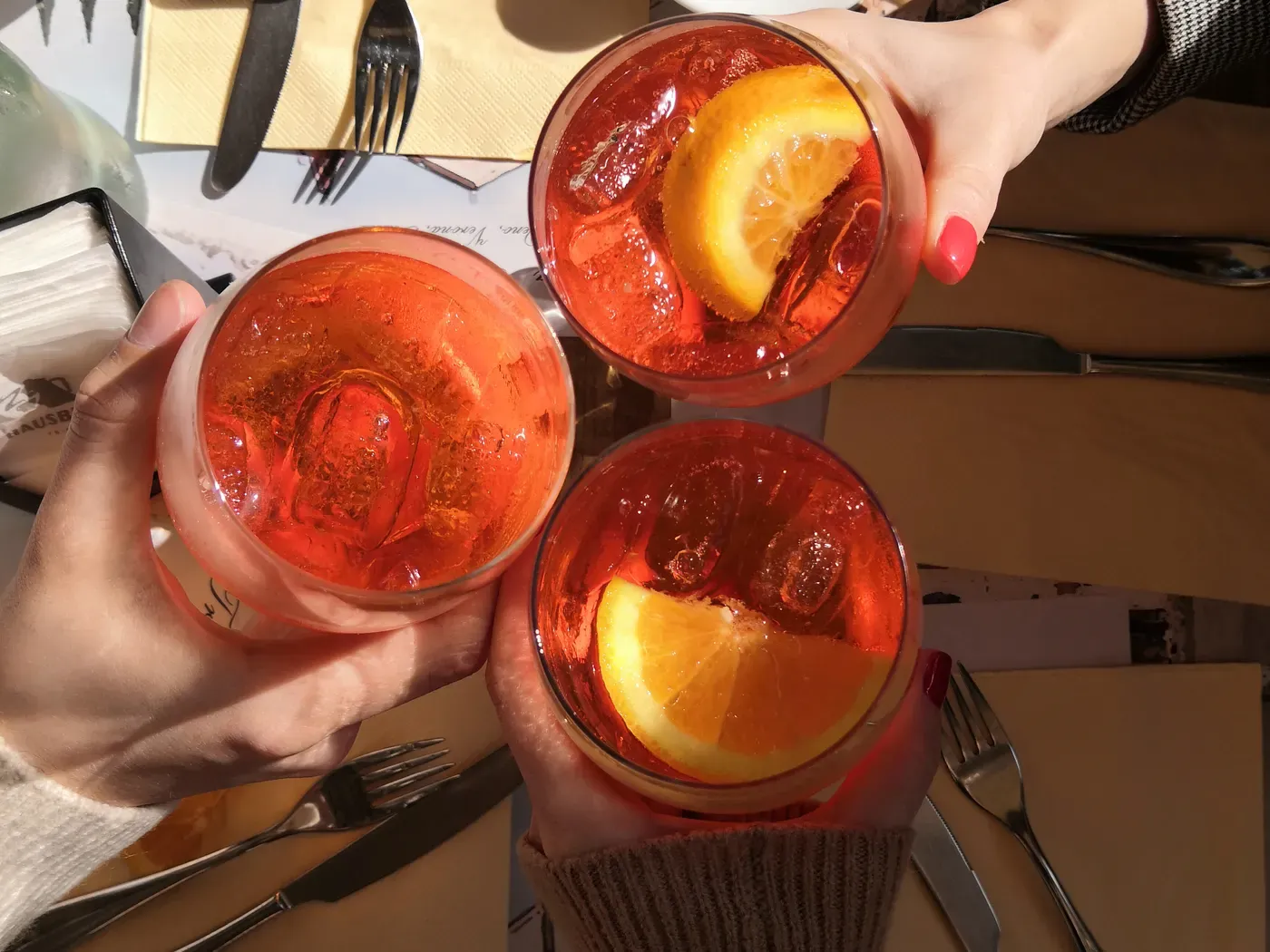 Freunde stoßen von oben gesehen mit orangefarbenen Aperitivo-Gläsern an