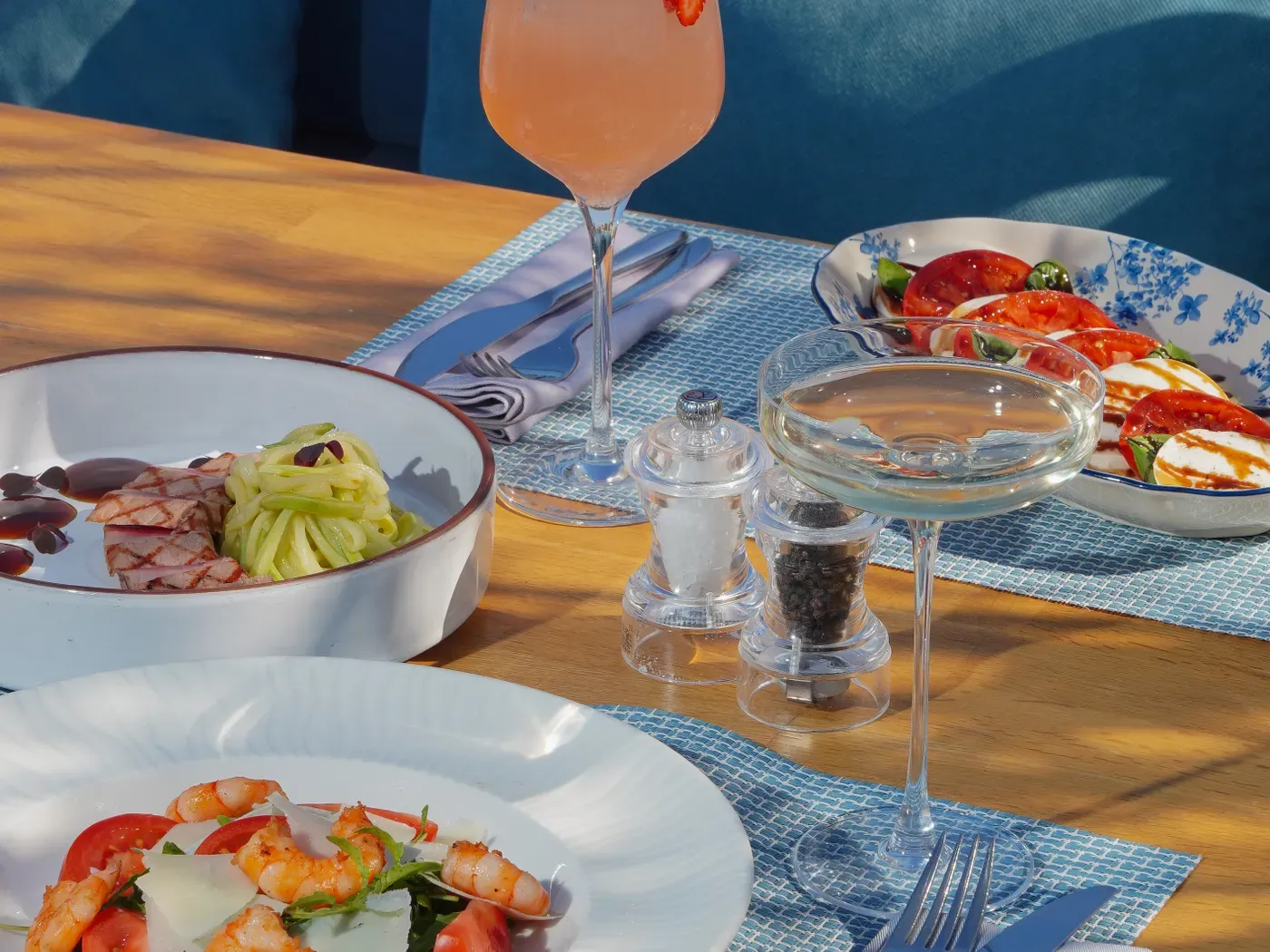 Gedeckter Tisch mit Meeresfrüchten und Aperitivo im Sonnenlicht