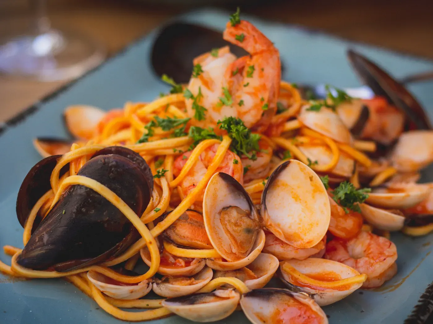 Meeresfrüchtepasta und Weißwein an einem hellen Tisch